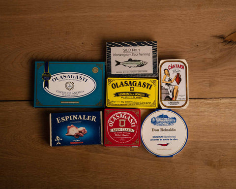 A selection of colourfully packaged tins of fish against a wood background