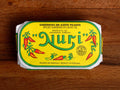 A tin of spicy sardines in a yellow wrap with a white and green border. Nuri is written in green lettering above some red chilli peppers.