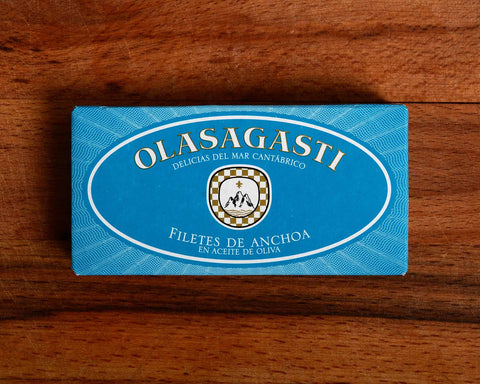 A tin of anchovies in light blue packaging with Olasagasti written in white lettering, on a wooden background