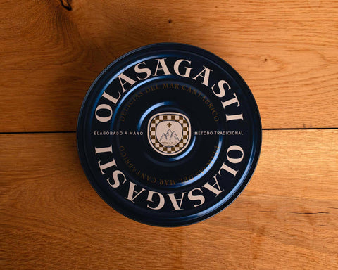A large circular tin of tuna. The lid is red with gold lettering round the sides.