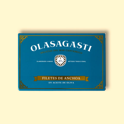 Olasagasti anchovy fillets blue packaging on a yellow surface. The design is simple with many details like a Sicilian coat of arms, a golden banner and decorative details on the corners.
