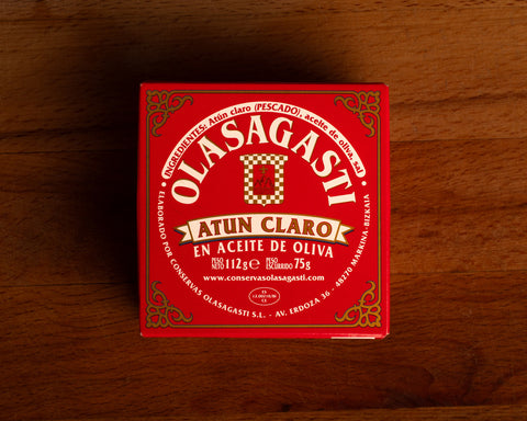 A square red box with Olasagasti written in white lettering inside an ornate gold border.