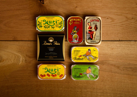 A selection of colourfully packaged tinned fish with a wood background