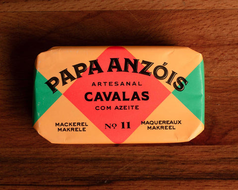 A tin of mackerel in olive oil from Papa Anzois, inside a brightly coloured orange, red and green packaging.
