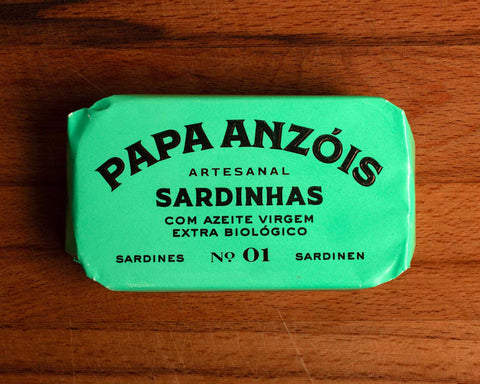 A tin of sardines in organic extra olive oil in light green packaging, featuring the Papa Anzóis brand name at the top.