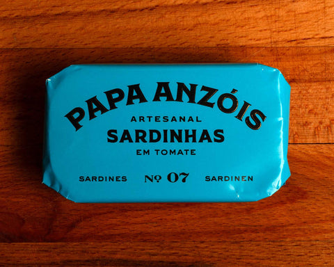 A tin of sardines in tomato sauce in blue packaging, with Papa Anzóis displayed at the top.