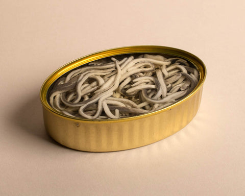 An opened tin of eels enriched in a succulent sauce. A gold trim throughout the whole tin.