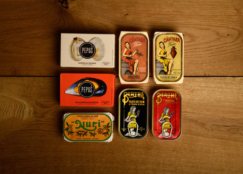 A selection of colourfully packaged tinned fish with a wood background