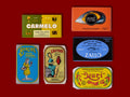 A selection of colourfully-packaged tinned sardines, tuna, mackerel, salmon and tasty sardines against a red background.