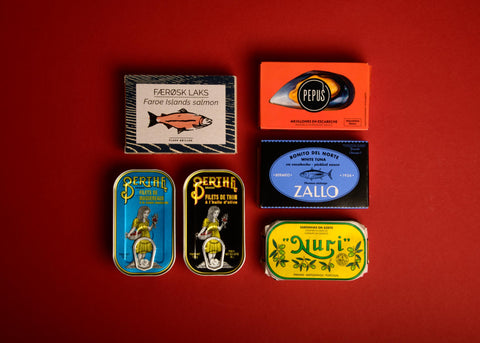 A selection of colourfully packaged tinned fish on a red background