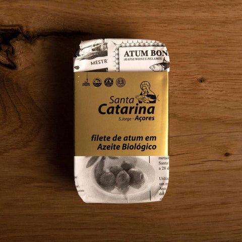 A tin of Santa Catarina tuna in black and white packaging with a gold label against a wood background