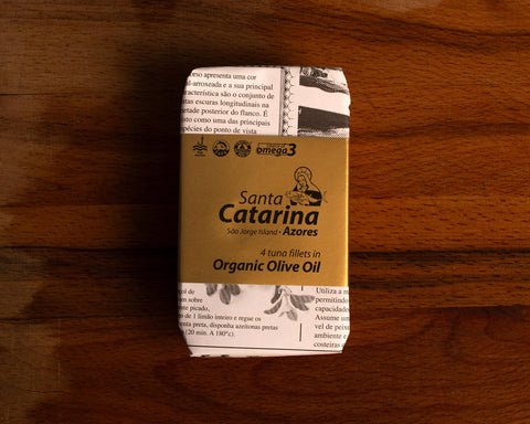 A tin of Santa Catarina tuna in black and white packaging with a gold label against a wood background