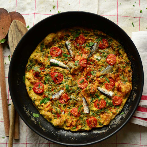 A delicious sardine omelette cooked to perfection. Placed gently on top of a red and white table cloth.