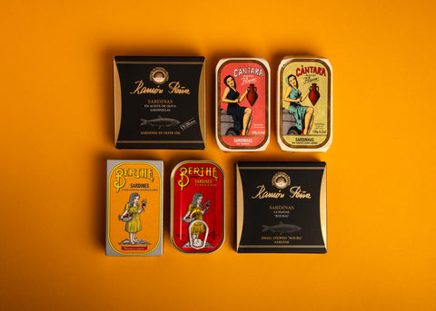 A selection of colourfully packaged tinned sardines on a yellow background