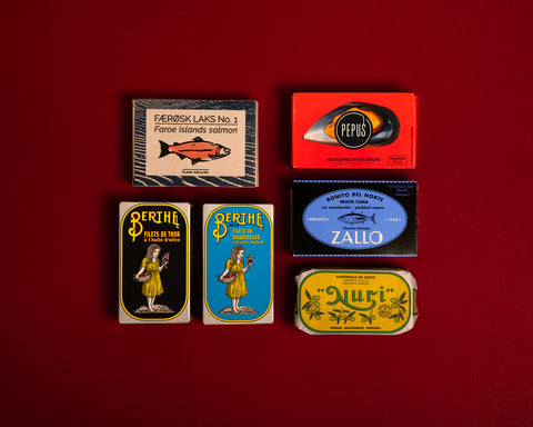 A selection of colourfully packaged tinned fish on a red background