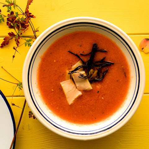 Tuna gazpacho, served in a white bowl with black trim and garnished with meaty flakes of bonito del norte & seaweed.