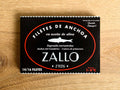 A tin of Cantabrian anchovies in black and red packaging against a light wood background.