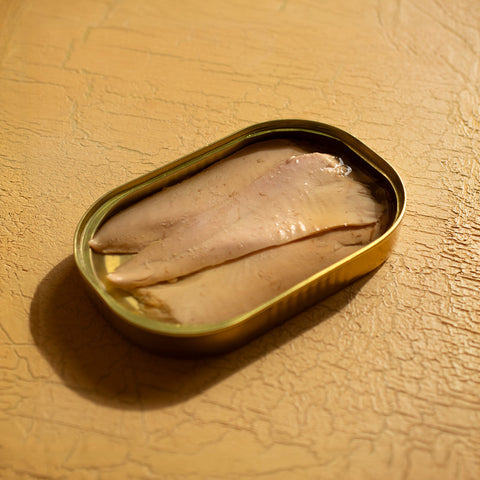 An large, rectangular open tin containing three fine slices of tuna belly.