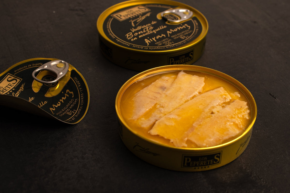 an open tin of ventresca tuna in golden, creamy butter. The tin is very luxurious, golden with a dark colour label and metallic writing.