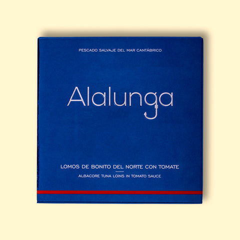 Tinned white tuna in square blue card packaging with Alalunga in silver, embossed lettering above a diagram of a tuna. There is a red stripe along the bottom of the packaging.
