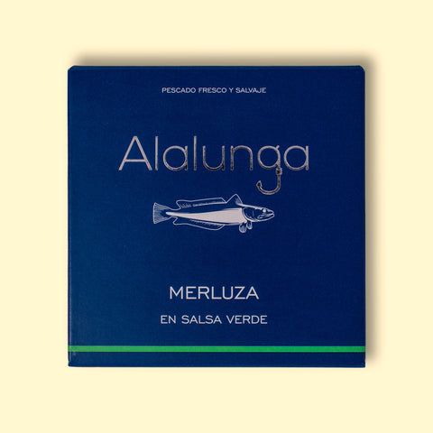 A tin of hake in salsa verde in blue card packaging  against a pale yellow background. The packaging has Alalunga written in silver lettering above a white illustration of a hake, and a green strip along the bottom.