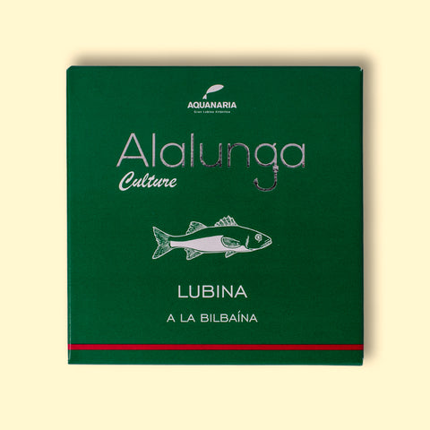 A tin of sea bass a la bilbaina or Bilbao style in green card packaging  against a wood background. The packaging has Alalunga written in silver lettering above a white illustration of a sea bass, and a red strip along the bottom.