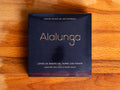 Canned white tuna in square blue card packaging with Alalunga in silver, embossed lettering above a diagram of a tuna. There is a red stripe along the bottom of the packaging.