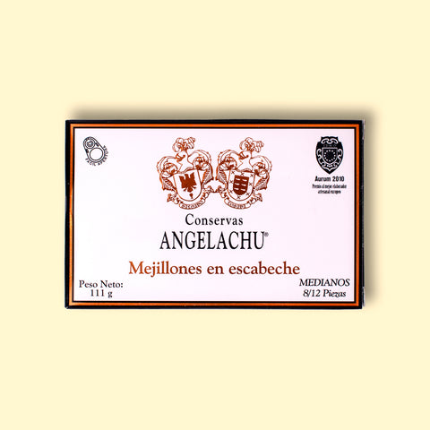 A tin of mussels in rectangular white card packaging with a black border with Angelachu written below two coats of arms
