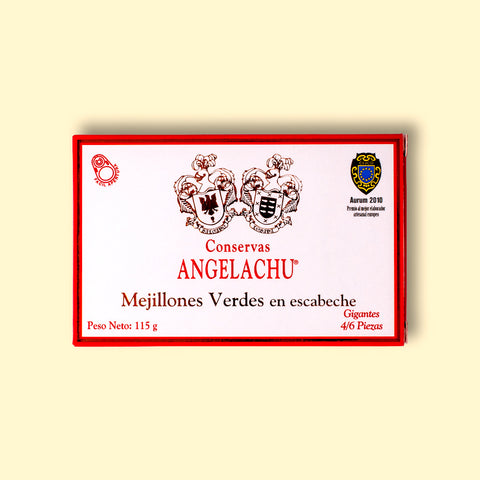 A tin of mussels in rectangular cardboard packaging. The packaging is white with an orange border. There are two coats of arms above Conservas Angelachu, which is written in orange lettering.