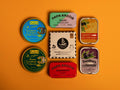 Collection of premium tins on an orange table. There are sardines, octopus and mussels from Spain and France