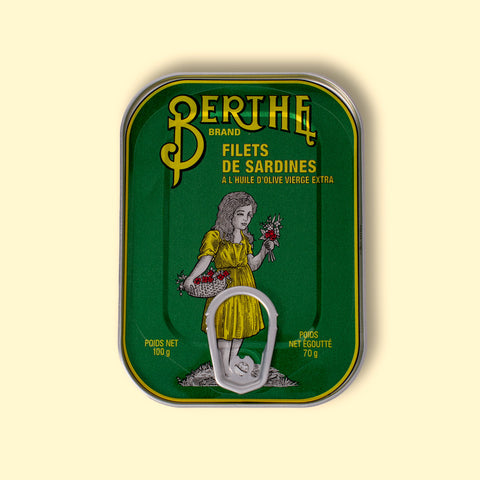 A bottle-green tin with an image of a girl in a yellow dress laminated onto the front of the tin 