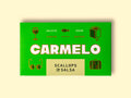 Carmelo scallops in salsa packaged in a bright green box on a pale wooden surface.