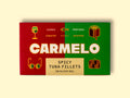 Carmelo spicy tuna fillets on a yellow wooden table. The paper box is green and red with big letters saying Carmelo and there are golden illustrations around the box