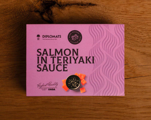 A can of salmon in purple card packaging with dark purple lettering. There is an image of diced salmon by a bowl of teriyaki sauce. 