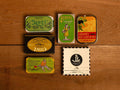 A selection of colourfully-packaged tinned sardines, mackerel and tuna against a wood background.