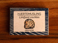 Limfjord cockles in white and blue packaging, featuring an illustration of a cockle, with text beneath reading lightly salted.