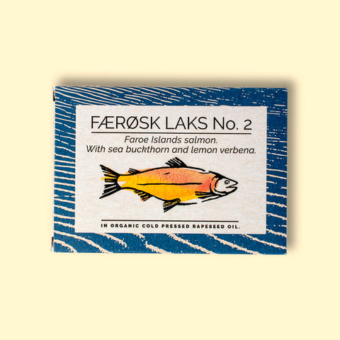 A tin of Faroe Islands salmon in white packaging with blue borders, featuring an illustration of a salmon with the description of sea buckthorn and lemon verbena below. 