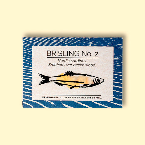 A tin of sprats in a rectangular box with a blue border and a painting of a yellow sprat on the front, against a dark wood background.