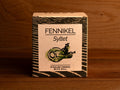 A tin of pickled with dill in light grey square card packaging with blue borders, featuring an illustration of a dill plant.