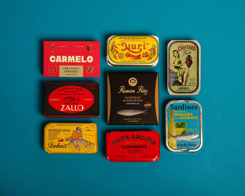 A selection of colourfully-packaged tinned mussels, sardines, tuna and mackerel against a blue background.