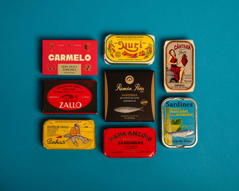 A selection of colourfully-packaged tinned mussels, sardines, tuna and mackerel against a blue background.