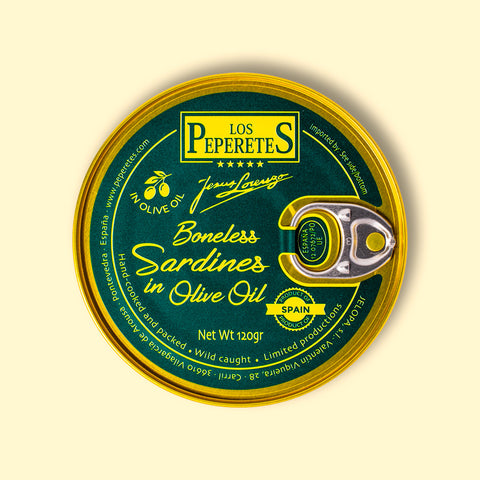 A tin of boneless sardines in green packaging with golden borders, featuring the Los Peperetes label at the top, set against a pale yellow wooden backdrop. 