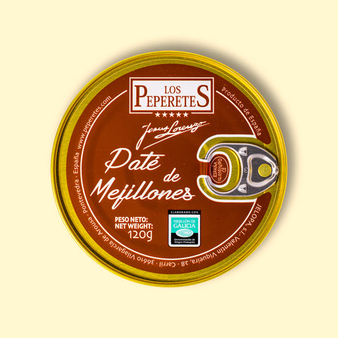 A circular tin of mussel pâté with a gold-coloured border, a silver ring pull, and a reddish brown label with the Los Peperetes logo at the top and pate de mejillones written in white lettering beneath it.