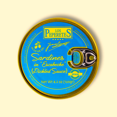A tin of sardines in escabeche, featuring light blue packaging with golden corners and the Los Peperetes label at the top, set against a yellow backdrop 