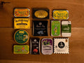A selection of colourfully-packaged tinned mussels, tuna belly, tuna, sardines and squid against a wood background.
