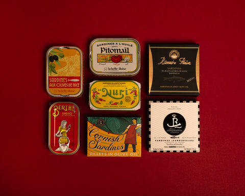 A selection of colourfully-packaged tinned sardines against a red background.