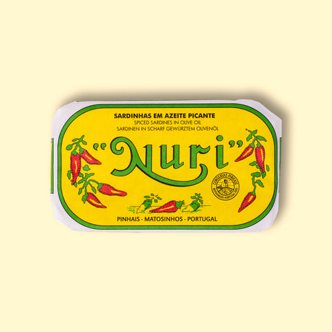 A tin of spicy sardines in a yellow wrap with a white and green border. Nuri is written in green lettering above some red chilli peppers.
