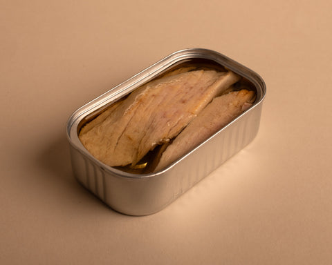 Open tin of ventresca tuna. Inside the tin you can see large flakes of delicious tuna in a golden olive oil