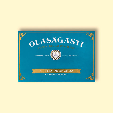 Olasagasti anchovy fillets blue packaging on a yellow surface. The design is simple with many details like a Sicilian coat of arms, a golden banner and decorative details on the corners.