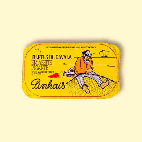 Mackerel fillets in a yellow paper wrap. There is a drawing of a red chilli pepper and a fisherman mending a fishing net on the front.